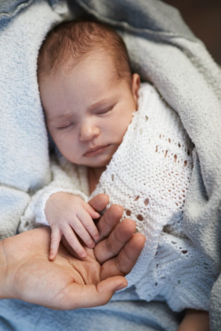 Mom keeps miniature hand newborn baby in hands